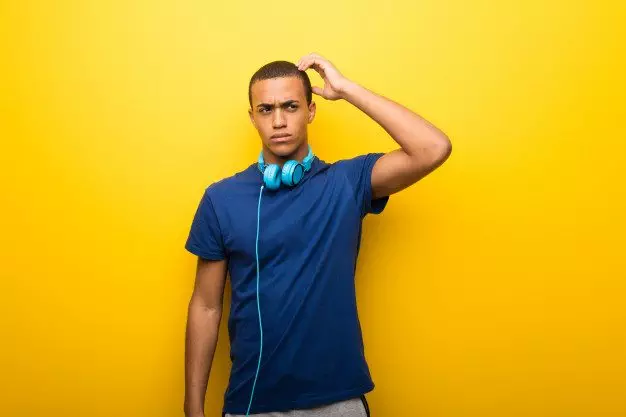 african american man with blue t shirt yellow background having doubts while scratching head 1368 26203 3