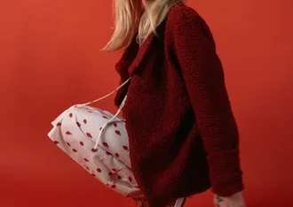 a woman in a red sweater is holding a white bag